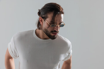 cool bearded man with rectangular sunglasses looking down side