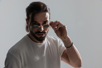 attractive young man looking forward and adjusting sunglasses