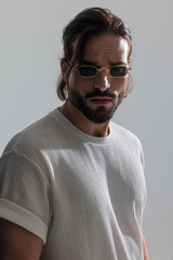 sexy young man with sunglasses posing in a cool way while looking forward