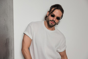 cool bearded man with sunglasses looking at camera and posing