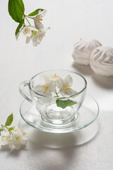Fragrant jasmine tea in a glass cup with marshmallows on a white wooden table.