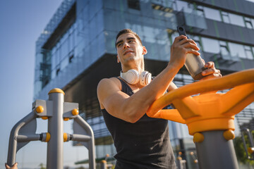One caucasian man young male athlete take a brake during outdoor training in the park outdoor gym...
