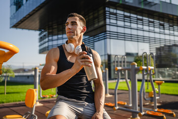 One caucasian man young male athlete take a brake during outdoor training in the park outdoor gym hold supplement shaker in hand happy confident strong copy space