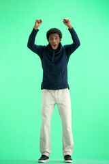 A man, full-length, on a green background, raised his hands up