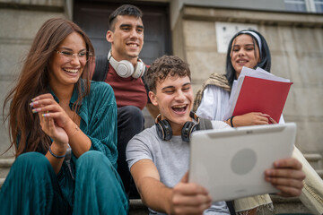 group of students sit in front of school watch video on digital tablet