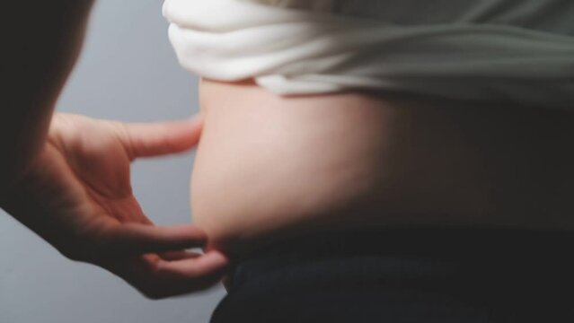 Man pointing own unhealthy big belly with visceral or subcutaneous fats. Pose health risk.