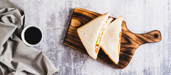 Club sandwich with chicken meat, tomato and lettuce on a board on the table top view web banner