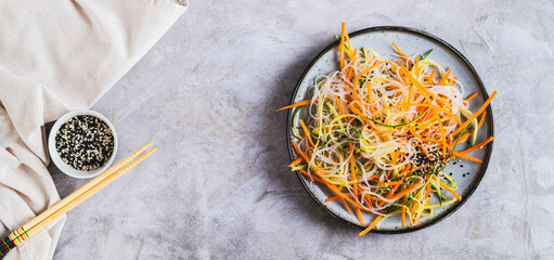 Funchoza salad with fresh cucumber and Korean carrots on a plate top view web banner