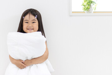 布団を持つ笑顔の女の子（3歳、日本人）