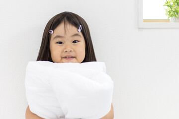布団を持つ笑顔の女の子（3歳、日本人）