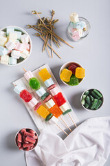 Marmalade candies-kebabs and marshmallows on skewers on the table top and vertical view
