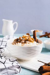 Rice pudding with cinnamon and cashews in a bowl on the table vertical view