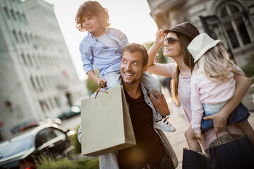 Happy family shopping in the city with two kids