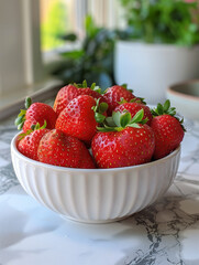 A white bowl filled with fresh, ripe strawberries on a marble countertop.