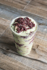 A view of a matcha smoothie with red bean topping.