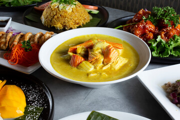 A view of a bowl of yellow curry, among other Asian entrees.