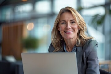 Mature businesswoman in office using laptop  smiling and working.