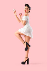 Young pin-up woman with tasty donuts on pink background