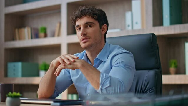 Portrait successful executive posing at office desk. Smiling brunette man look