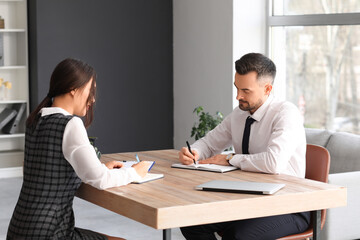 Human resources manager interviewing applicant at table in office