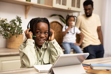 Multicultural little girl using digital software on tablet for online education