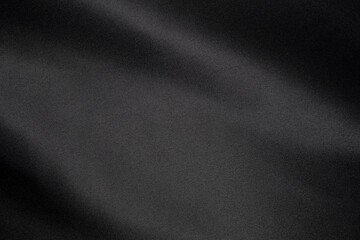 Close-up of a smooth, slightly reflective black fabric showcasing its texture and subtle lighting...