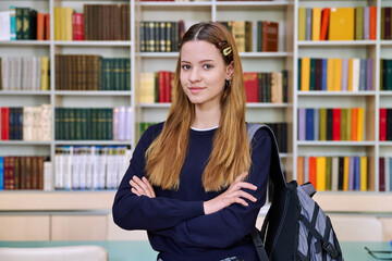 Portrait of high school student girl with backpack in library classroom