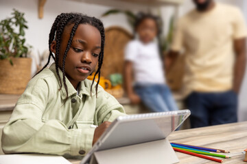 Little girl browsing internet on her tablet exploring educational websites for her school project