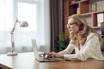 Fototapeta premium Elegant female psychologist working in modern office using portable computer
