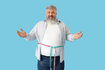 Overweight mature man with measuring tapes on blue background. Weight loss concept