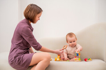 A woman is holding a baby and playing with a toy.