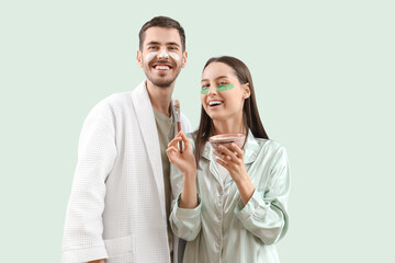 Young loving couple with facial mask on green background