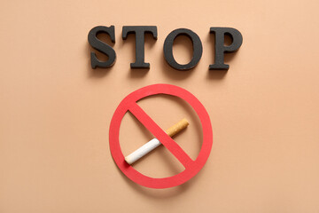 Stop sign with cigarette and wooden word STOP on beige background. Stop smoking concept.