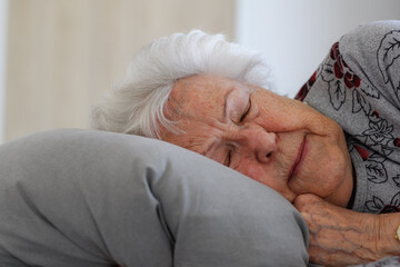 Senior woman sleeping in her bed alone, feeling anxious. Loneliness, social isolation of eldery...
