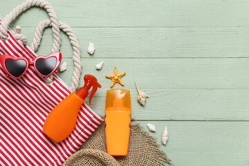 Bag, bottles of sunscreen and beach accessories on wooden background
