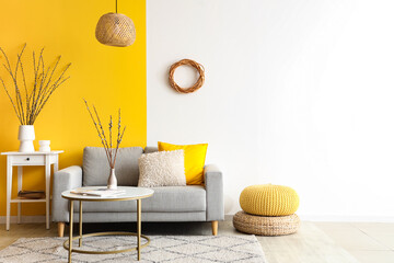 Interior of living room with sofa, tables and willow branches in vases