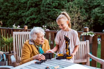 Grandmother supporting granddaughter in robotics, science, IT technologies and programming. Young...