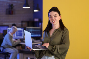 Female programmer working with laptop in office at night
