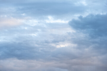 Moody, cloudy sky at dusk with a hint of warm color in blue clouds, as a nature background
