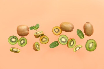 Ripe cut kiwi and mint leaves flying against color background