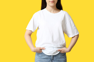Pretty young woman in stylish white t-shirt on yellow background