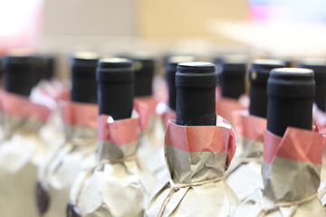 A row of wine bottles with ribbons tied around the necks