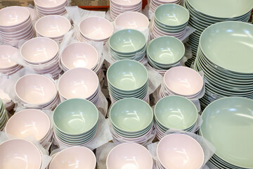 A large pile of white and pink bowls and plates