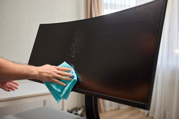 A person is using a cloth to clean a flat screen TV