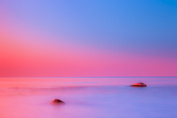 Romantic pink sky over rocks in Baltic Sea at sunrise, Lithuania