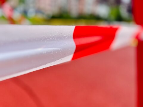 Close-up of a piece of wet plastic red and white cordon tape