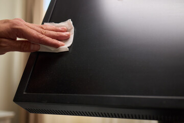 A person is using a cloth to clean a flat screen TV