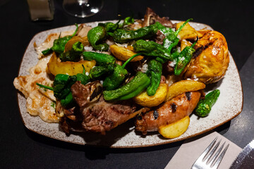 Appetizing grilled mix from chicken fillet, veal steak and pork sausages served with baked potatoes and jalapenos