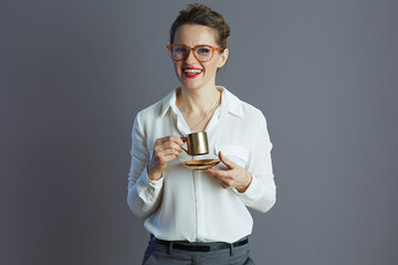 smiling trendy woman worker in white blouse isolated on grey