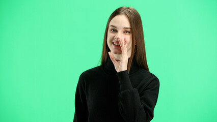 A woman, close-up, on a green background, tells a secret